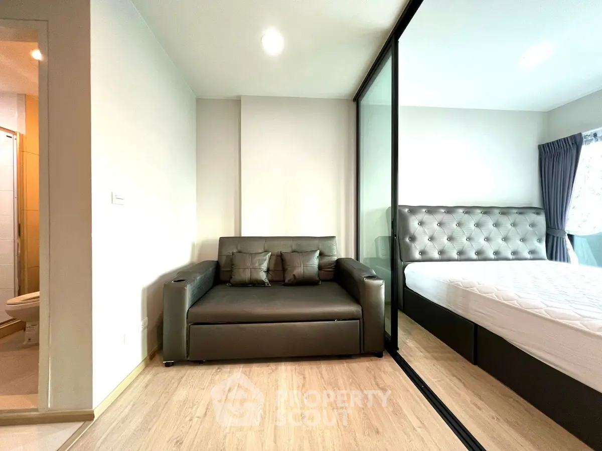 Modern studio apartment with glass partition and stylish furnishings.