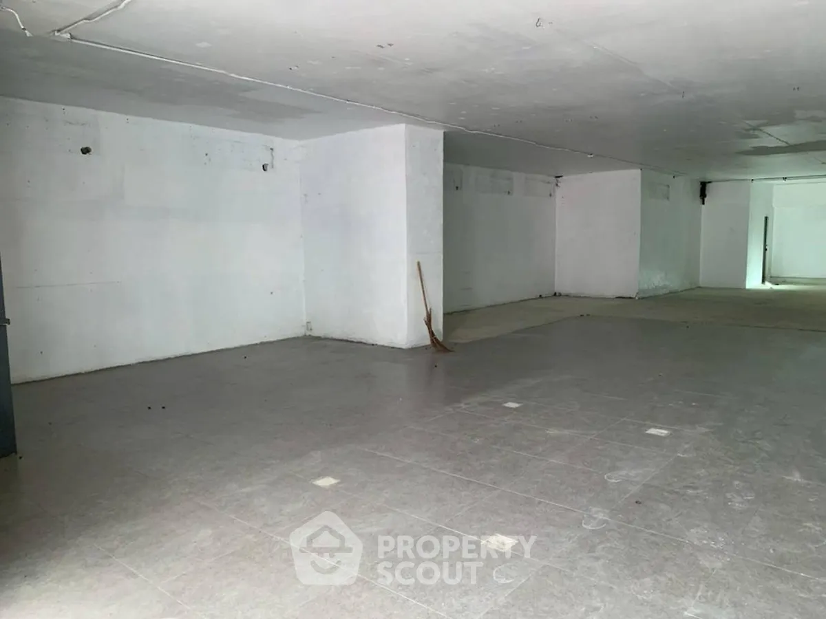 Spacious unfinished basement with tiled flooring, ideal for storage or renovation.