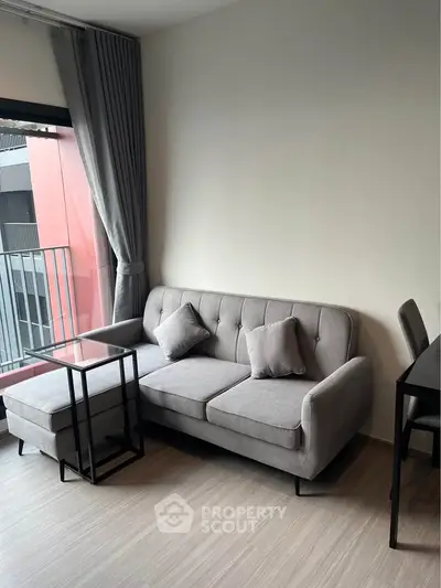 Modern living room with stylish gray sofa and natural light from balcony.