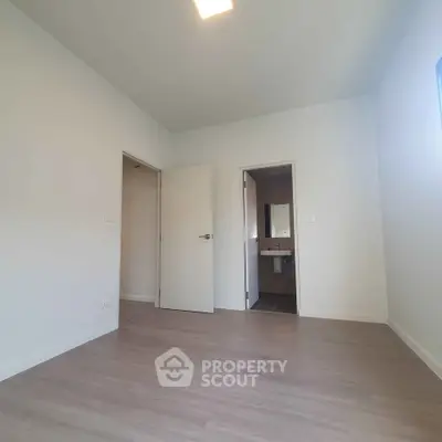 Spacious bedroom with ensuite bathroom and modern flooring in a bright, minimalist design.