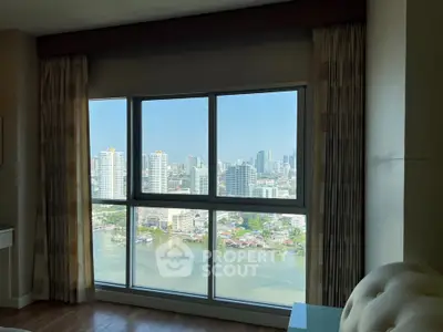 Stunning high-rise apartment with panoramic city and river views from large window.