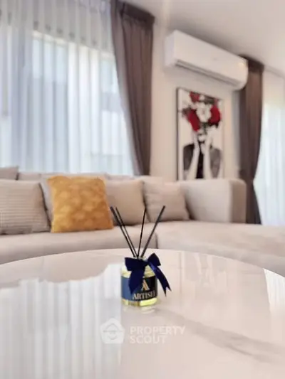 Elegant living room with modern decor and air conditioning, featuring a stylish sofa and artistic wall art.