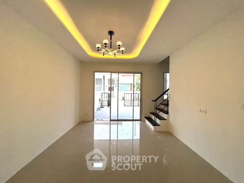 Spacious modern living room with elegant lighting and large glass doors leading to a patio.