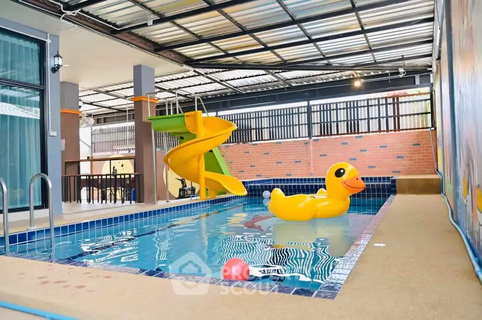 Charming indoor pool with slide and playful duck float in modern real estate property.