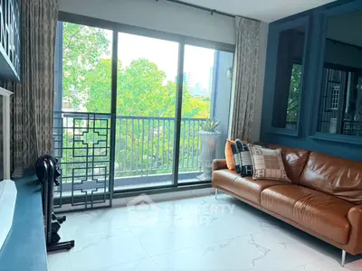 Modern living room with large windows and balcony overlooking lush greenery.