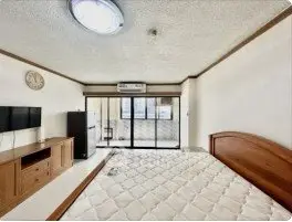 Spacious bedroom with large window and modern furnishings in a bright apartment.