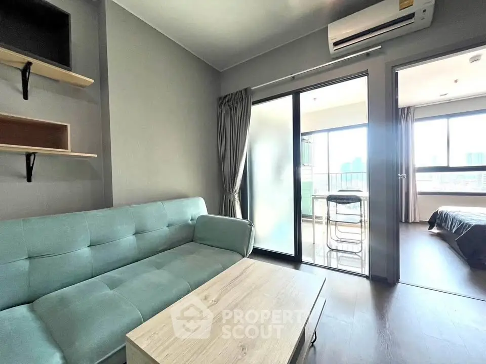 Modern living room with balcony access and city view, featuring stylish furniture and air conditioning.