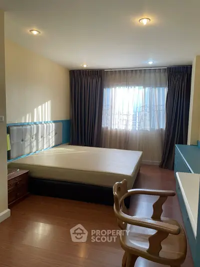 Spacious bedroom with large window and elegant furnishings, perfect for relaxation.