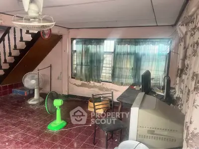 Spacious living area with large windows and staircase, ideal for renovation.