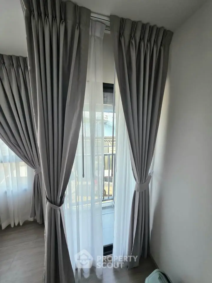Elegant corner unit with floor-to-ceiling windows and stylish curtains, offering a glimpse of the serene outdoor view.