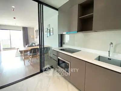 Modern open-layout kitchen with sleek cabinetry and dining area in a bright apartment.