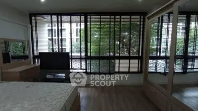 Spacious bedroom with large windows and modern furnishings in a stylish apartment.