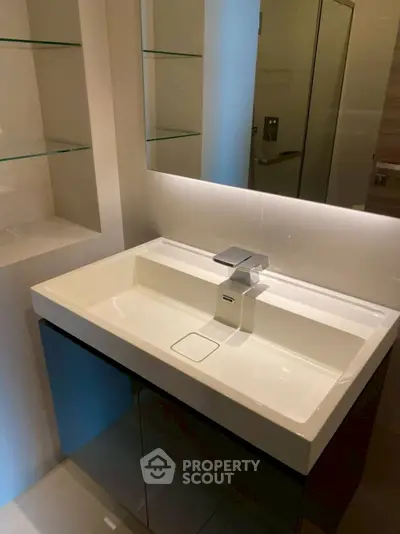 Modern bathroom with sleek sink and glass shelves, perfect for contemporary living.