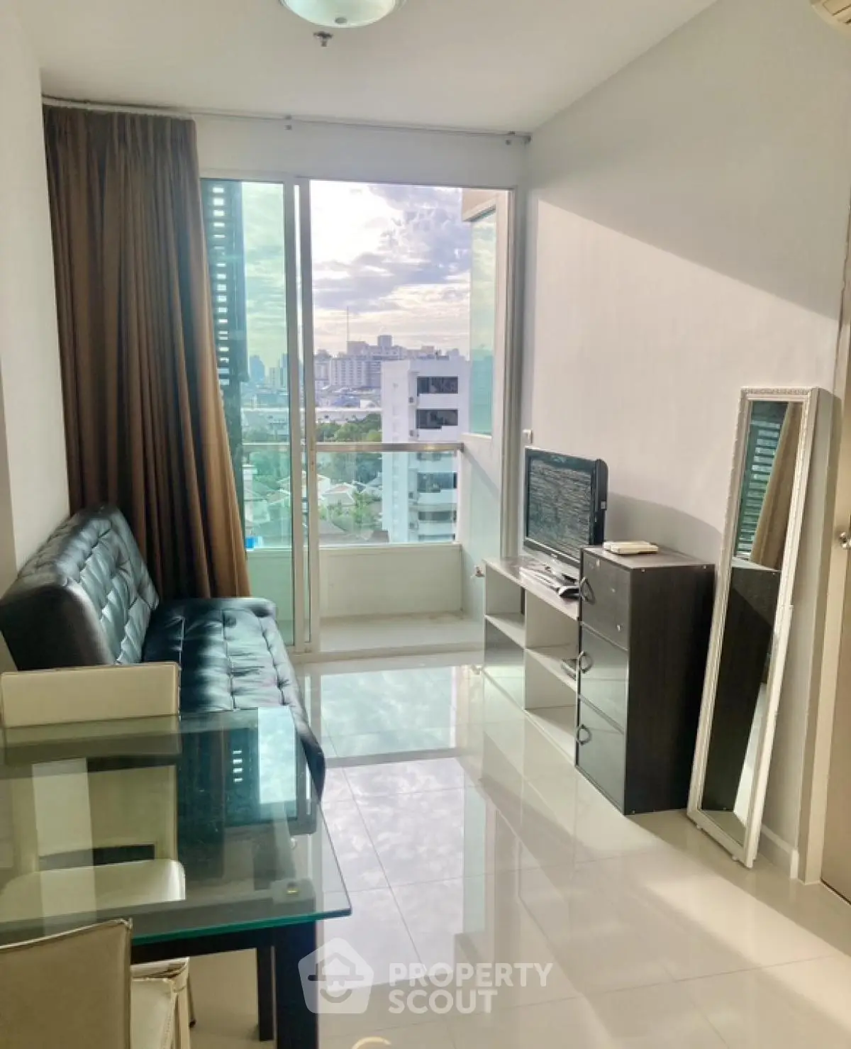 Modern living room with city view, glass table, and sleek furniture in a high-rise apartment.