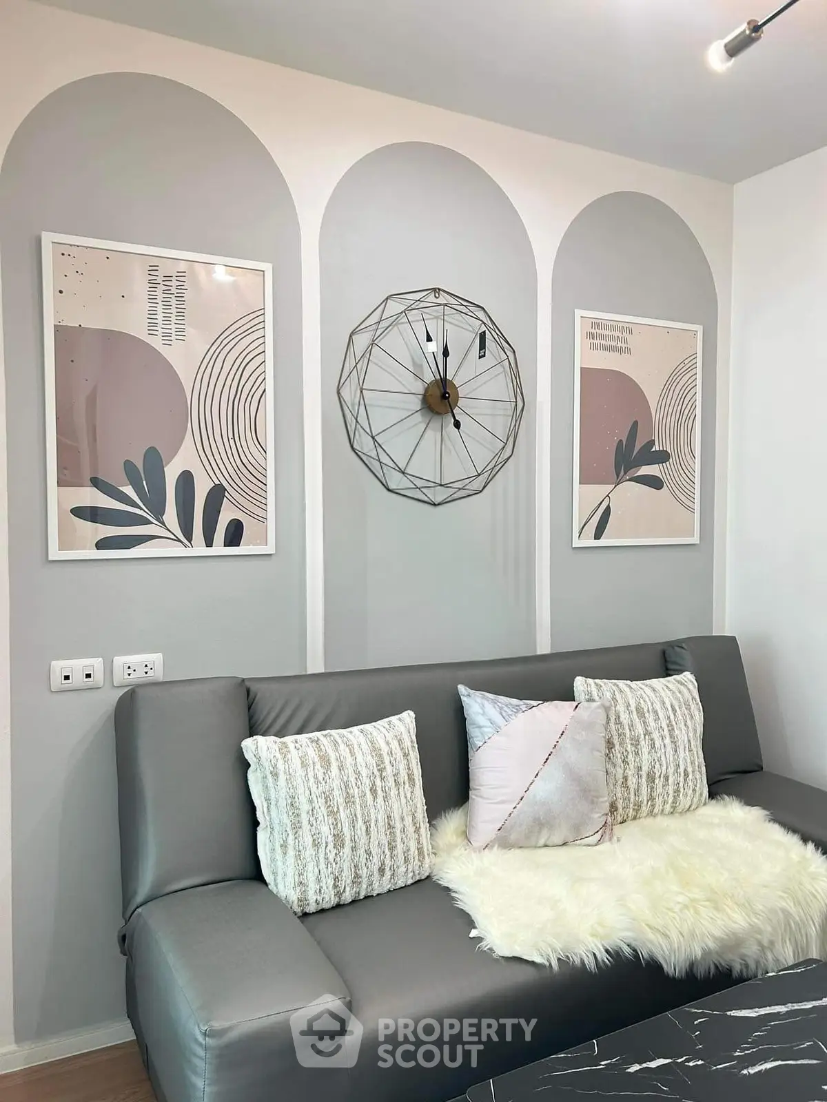 Stylish modern living room with gray sofa, abstract art, and unique wall clock.