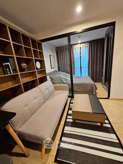 Modern living room with cozy sofa, stylish coffee table, and view into a bedroom through glass doors.