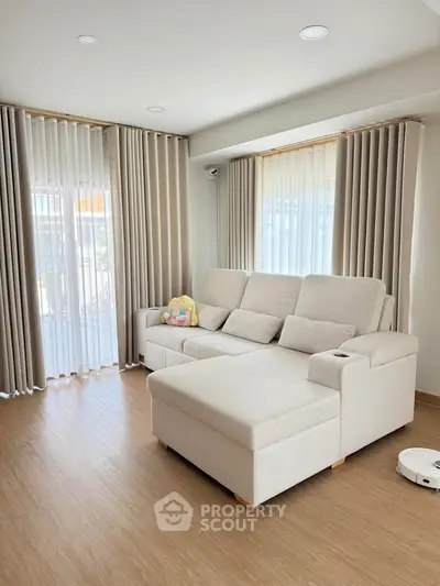 Spacious living room with modern beige sofa and elegant curtains