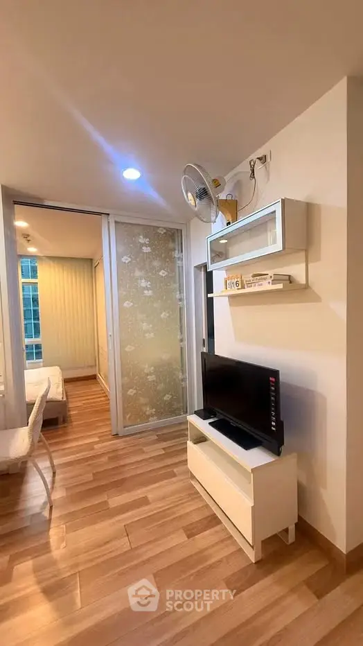 Modern apartment interior with wooden flooring and sliding glass door to bedroom