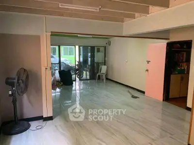 Spacious open-plan living area with marble flooring and natural light.