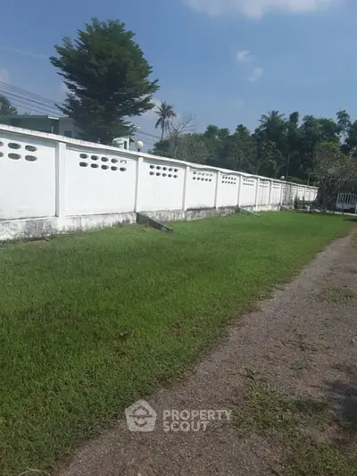 Spacious garden area with white boundary wall and lush greenery
