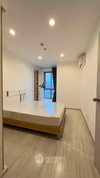 Spacious bedroom with modern design and large window offering natural light.