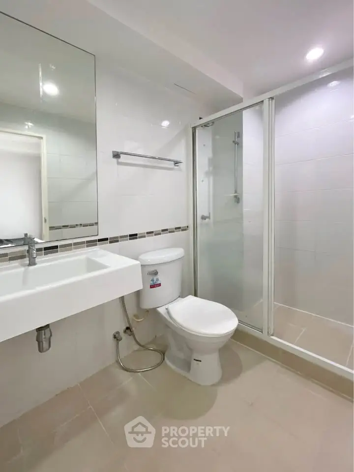 Modern bathroom with glass shower and sleek fixtures in a contemporary apartment.