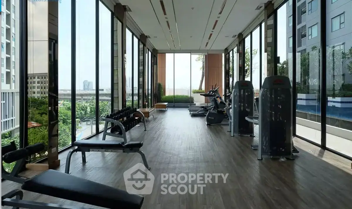 Spacious modern gym with panoramic city views in luxury high-rise building.