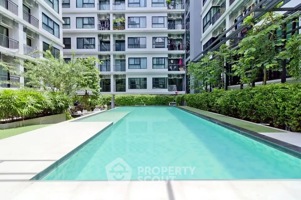 Luxurious apartment complex with a pristine swimming pool and lush greenery, perfect for relaxation and leisure.