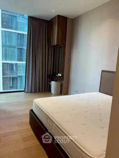 Modern bedroom with large window and wooden flooring in luxury apartment