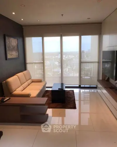 Modern living room with sleek furniture and large windows offering a stunning city view.