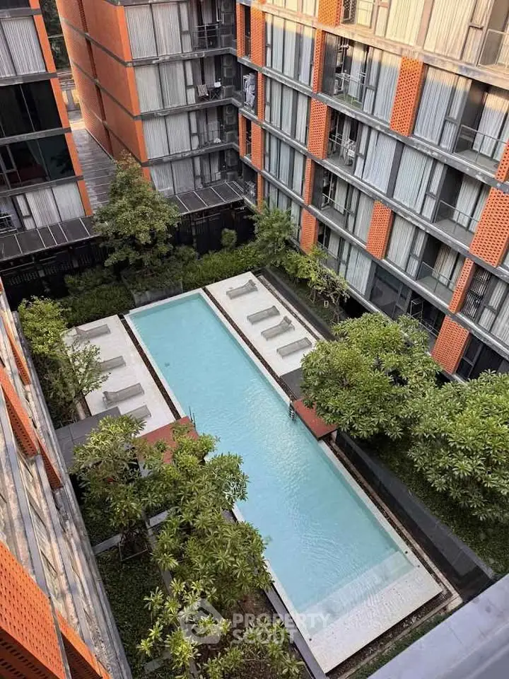 Modern apartment complex with central swimming pool and lush greenery.