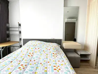 Modern bedroom with stylish decor and ample natural light, featuring a cozy bed and functional furniture.