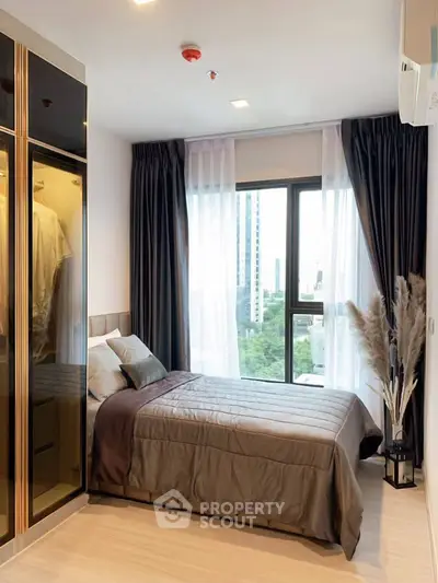 Modern bedroom with large window and stylish decor in urban apartment.