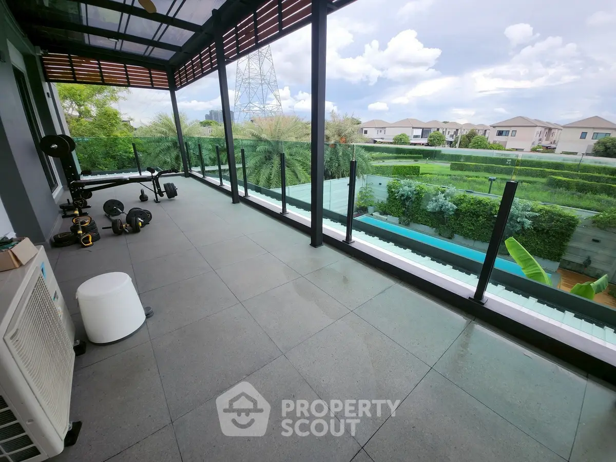 Spacious balcony with fitness equipment and scenic view of lush greenery.