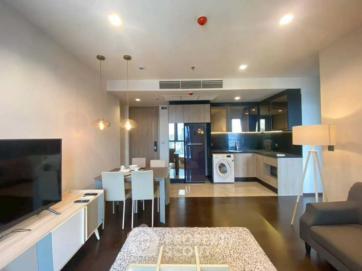 Modern open-plan living room with dining area and kitchen featuring sleek appliances.