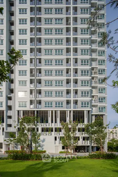 Modern high-rise apartment building with lush green landscaping