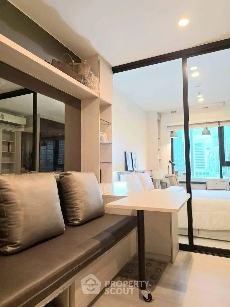 Modern studio apartment with sleek interior design and city view, featuring a cozy seating area and stylish decor.