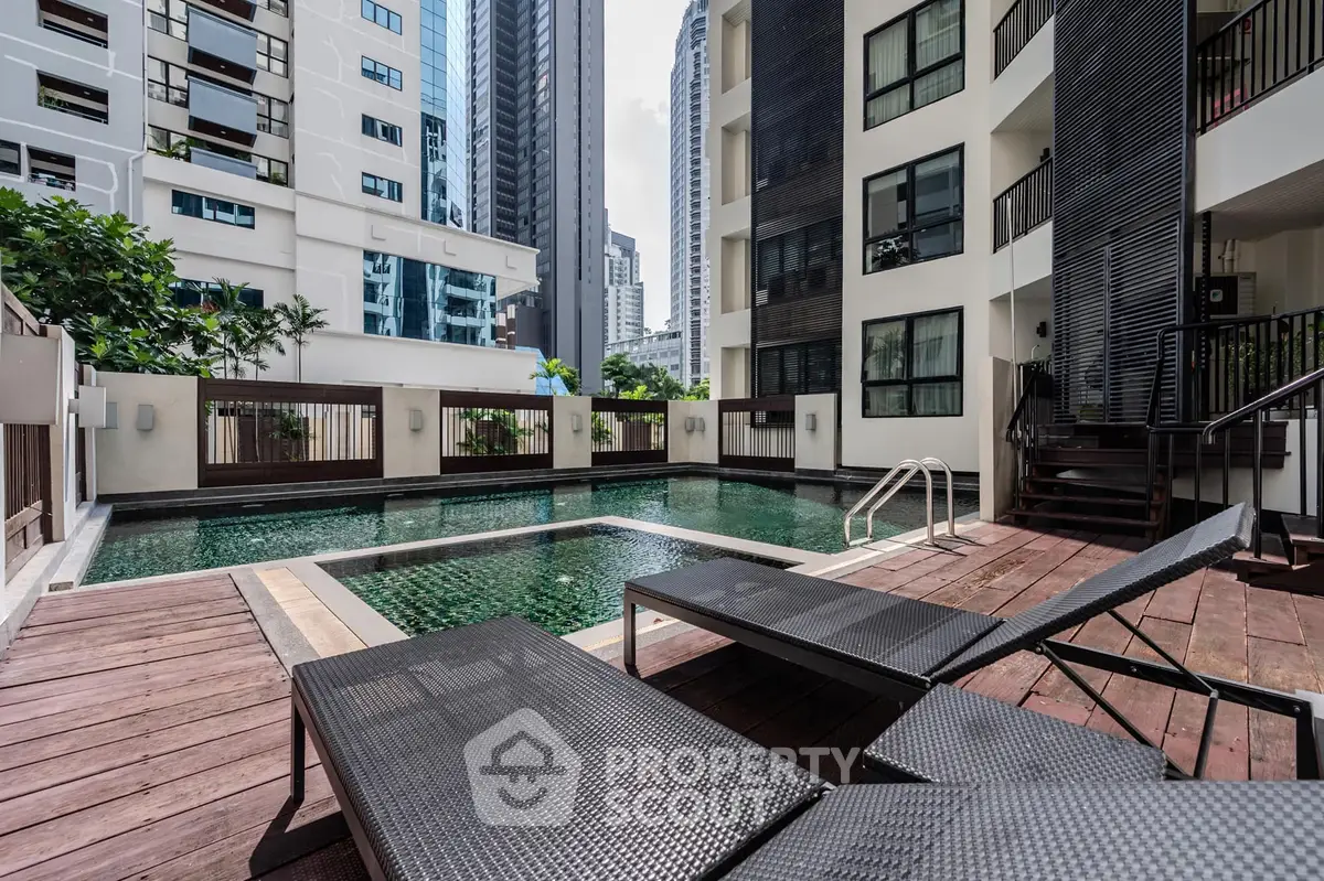 Luxurious urban apartment pool area with modern lounge chairs and cityscape view.