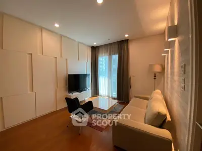 Modern living room with sleek furniture and large TV, featuring elegant lighting and wooden flooring.