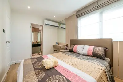 Modern bedroom with stylish decor and natural light, featuring a comfortable bed and elegant furnishings.