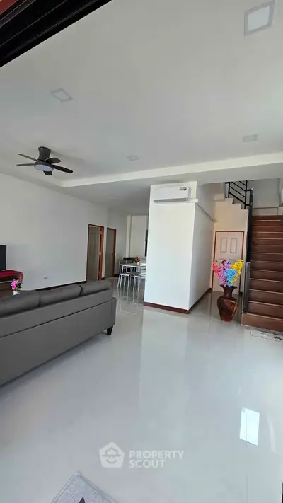 Spacious modern living room with sleek design and staircase, perfect for family gatherings.