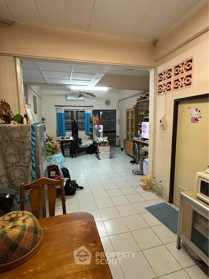 Cozy living room with tiled flooring and eclectic decor, featuring a mix of furniture and appliances.