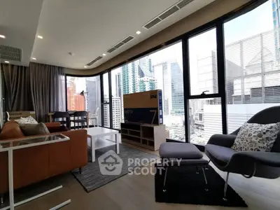 Modern living room with city view, stylish furniture, and large windows in a high-rise apartment.
