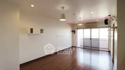 Spacious empty living room with wooden flooring and balcony access