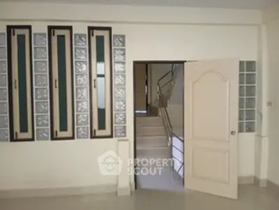 Spacious interior with unique glass block windows and open door leading to staircase.