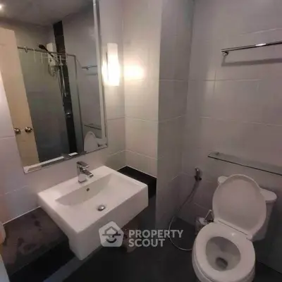 Modern bathroom with sleek fixtures and contemporary design, featuring a square sink and wall-mounted toilet.