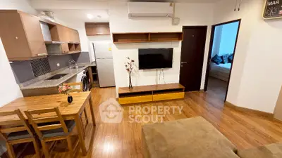 Modern open-layout living room with kitchen, featuring wooden flooring and contemporary furniture.