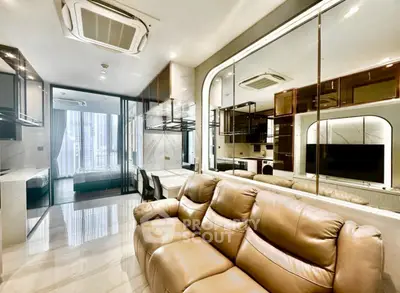 Luxurious modern living room with leather sofa and glass partition leading to a stylish bedroom.