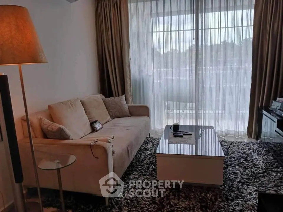 Cozy living room with plush sofa, stylish lamp, and large window with sheer curtains.