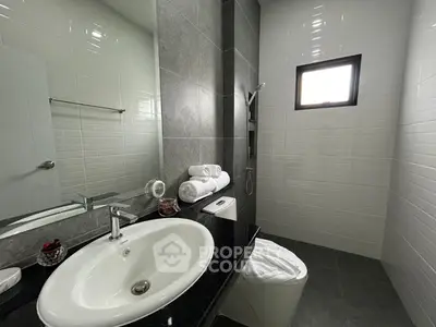 Modern bathroom with sleek design featuring a large mirror, elegant sink, and stylish tiles.